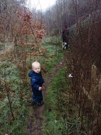 Boy standing by tree in forest