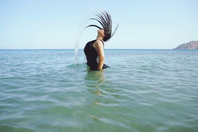 Woman in sea against sky