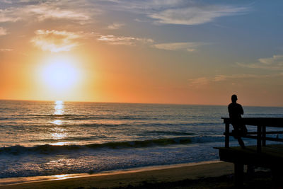 Silhouette man standing on beach against sky during sunset