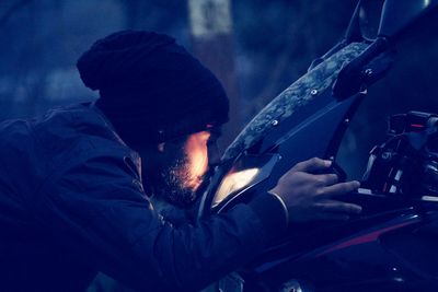 Man kissing motorcycle at night