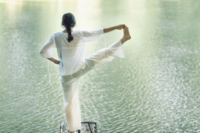 Woman practicing yoga near water in the nature. doing extended hand to big toe pose