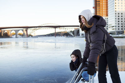 Young women standing at river in winter