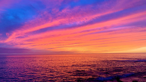 Scenic view of sea against dramatic sky during sunset