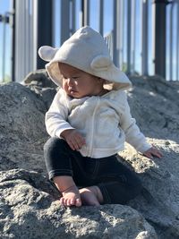 Full length of cute baby sitting on rock