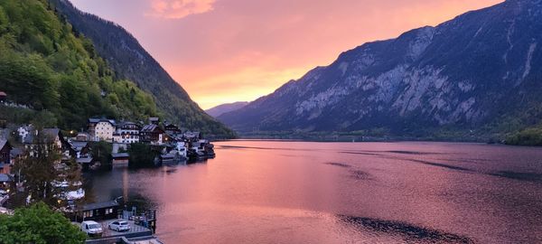 Scenic view of sea by mountains against sky during sunset