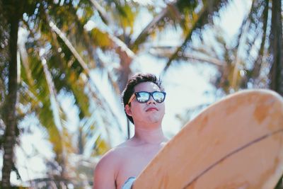 Portrait of shirtless man wearing sunglasses against trees