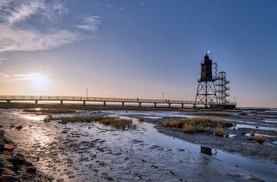 Lighthouse by sea against sky during sunset