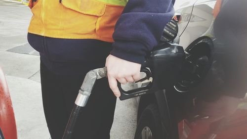 Midsection of man refueling gasoline in car at gas station