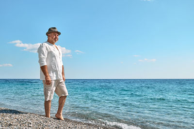 Happy middle-aged bearded man walking along beach. concept of leisure activities, wellness, freedom