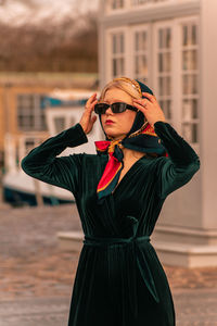 Portrait of young woman standing against building