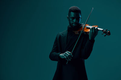 Low angle view of man playing violin against black background