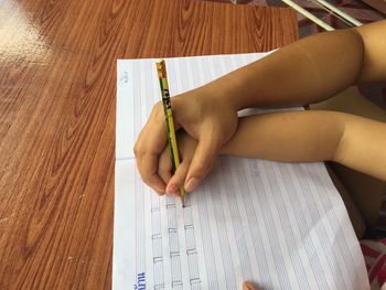 Cropped hand of person teaching child to write