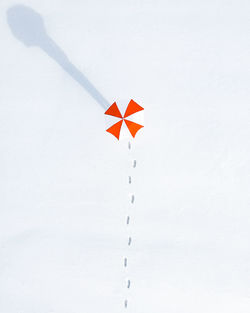 Close-up of shadow of person holding umbrella on snow covered field