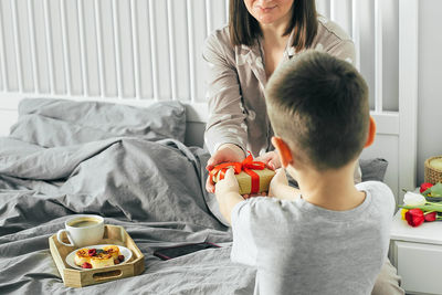 Rear view of mother with daughter on bed