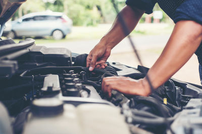 Cropped hands of man repairing engine of car