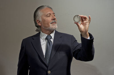 Mid adult man holding camera while standing against glass