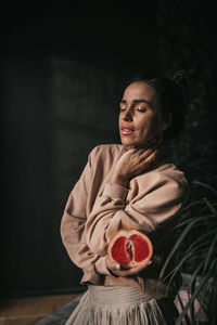 Woman looking away while standing against wall