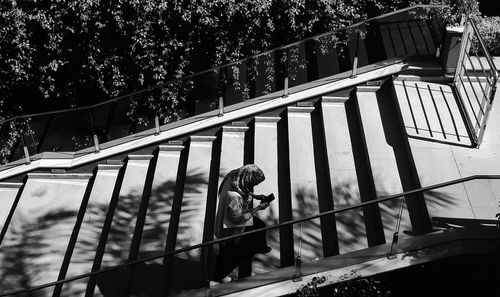 High angle view of woman using smart phone while moving up on steps