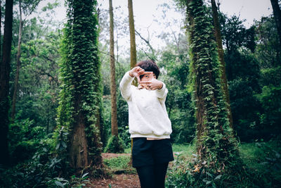 Portrait of woman looking through finger frame