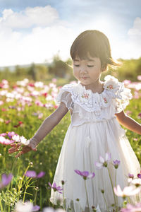 Rear view of girl standing by flowering plants