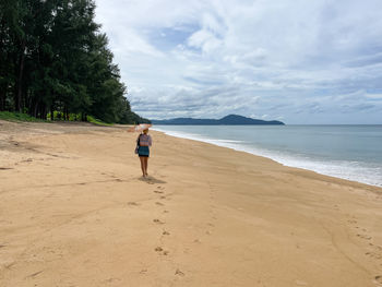 Woman walking on the beach in phuket holding an umbrella