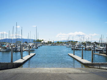 Sailboats moored at harbor against blue sky