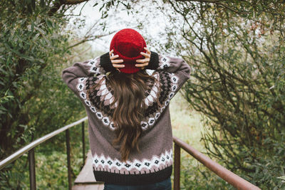 Young woman wearing hat standing against trees during winter