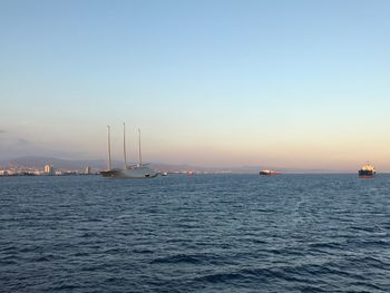 Sailboats sailing in sea against clear sky