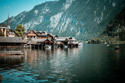 Houses by lake and buildings against sky