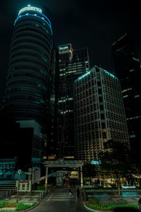 Illuminated city street and buildings against sky at night