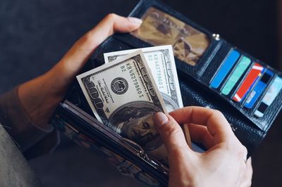 Midsection of woman removing paper currency from wallet