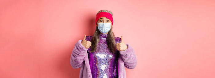 Low section of woman holding paper currency against yellow background