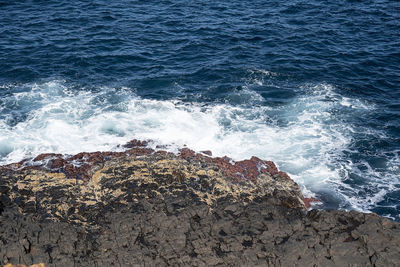 High angle view of waves splashing on rocks