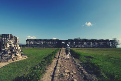 Built structure on grassy field against cloudy sky