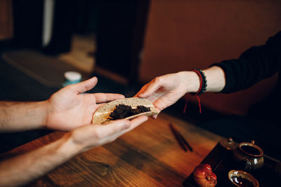 Cropped hand of woman holding food on table