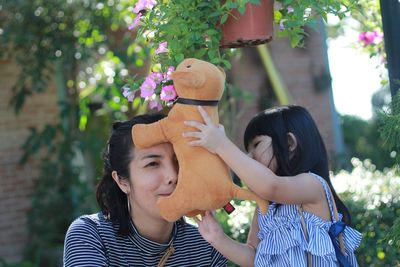 Mother and daughter playing with stuffed toy at yard