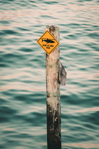 Close-up of sign on wooden post in lake