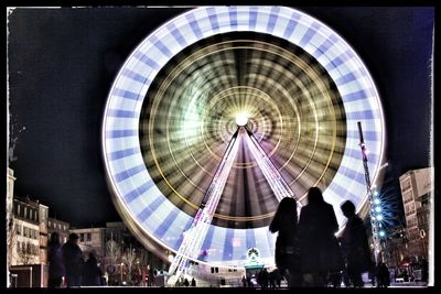 Illuminated ferris wheel against sky