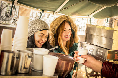 Smiling young woman holding coffee at store