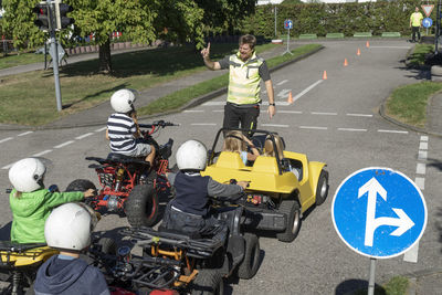 Trainer instructing children sitting on quadbikes at race traffic education training