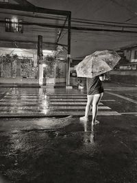 Rear view of woman walking on wet road during monsoon