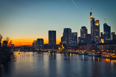 Illuminated buildings in city against sky during sunset