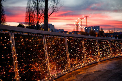 Illuminated city against sky at sunset