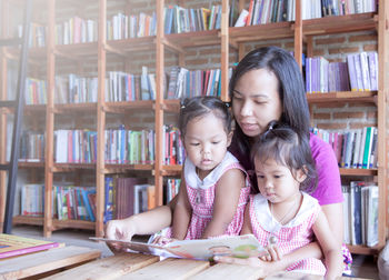 Mother showing book to daughters at home