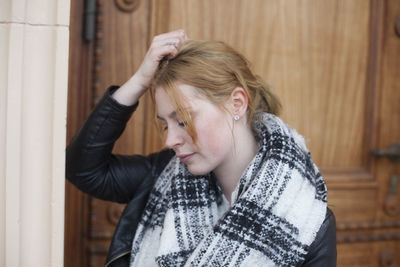 Sad woman standing against wooden door