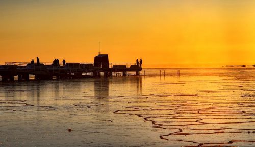 Pier on sea at sunset