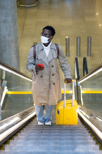 Side view of toy man wearing mask standing on escalator