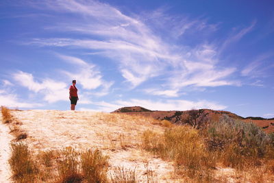 Low angle view of woman standing on arid hill against sky during sunny day
