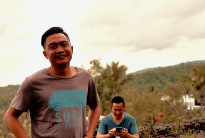 Portrait of smiling young man standing against sky