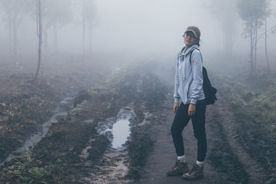 Portrait of woman standing in forest during foggy weather